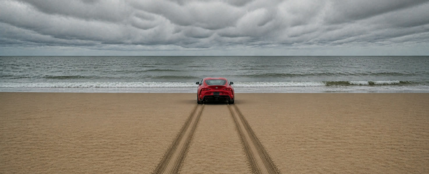 Rode sportauto staat op het strand met bandensporen in het zand, gericht op de zee onder een bewolkte lucht
